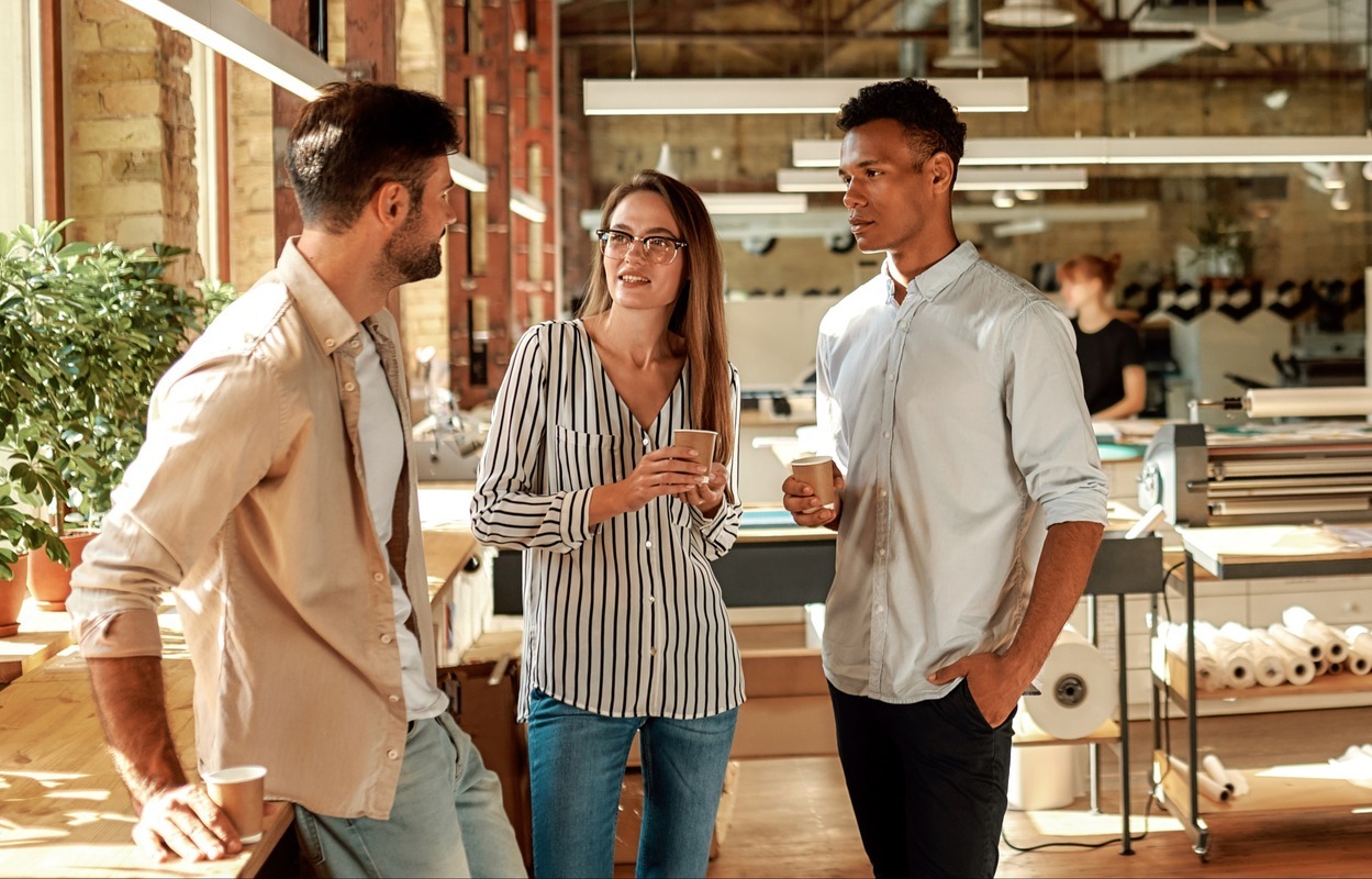 nice-talk-three-young-colleagues-casual-wear-holding-coffee-cups-discussing-something-while-1