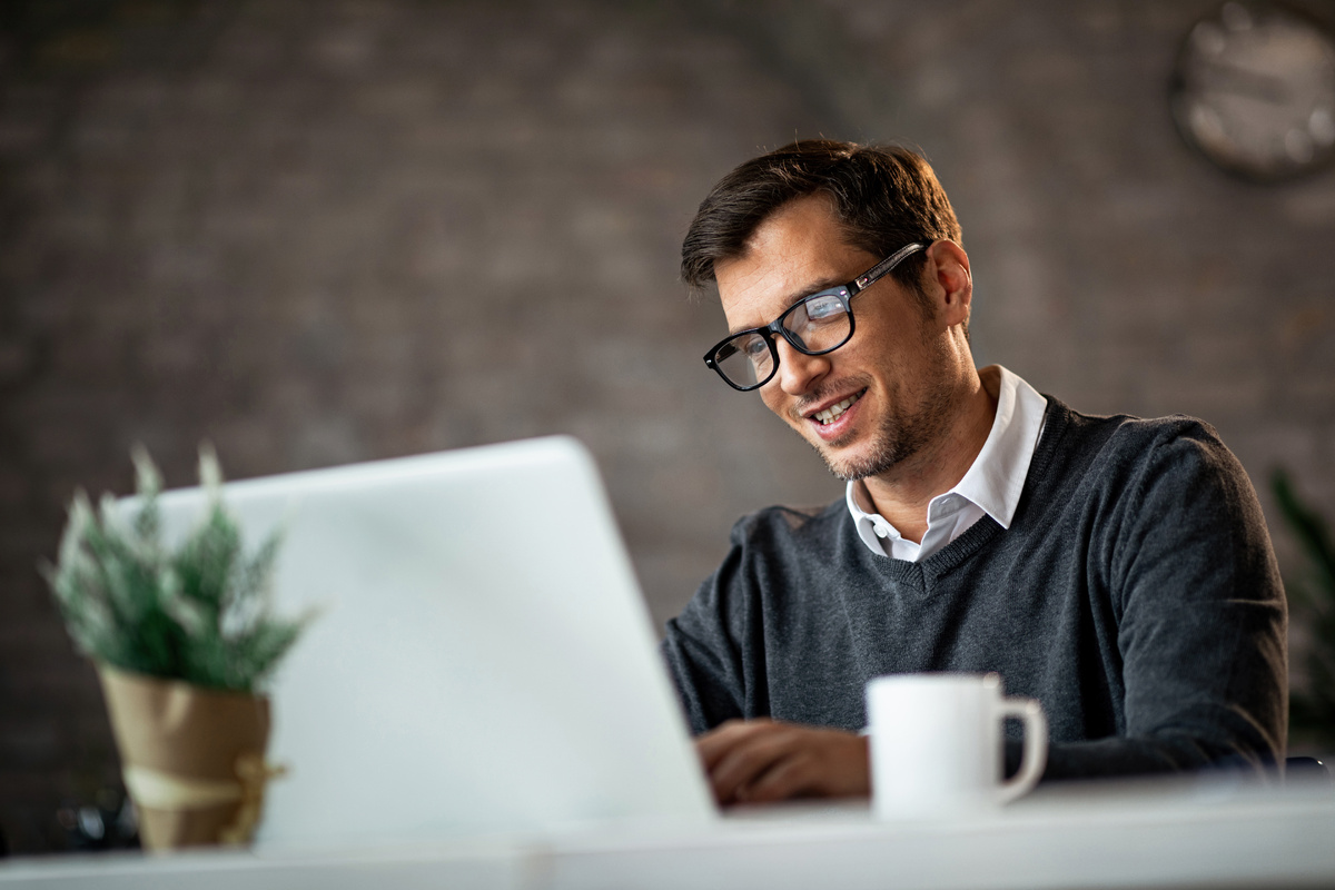 smiling-businessman-working-laptop-while-sitting-desk-office-1