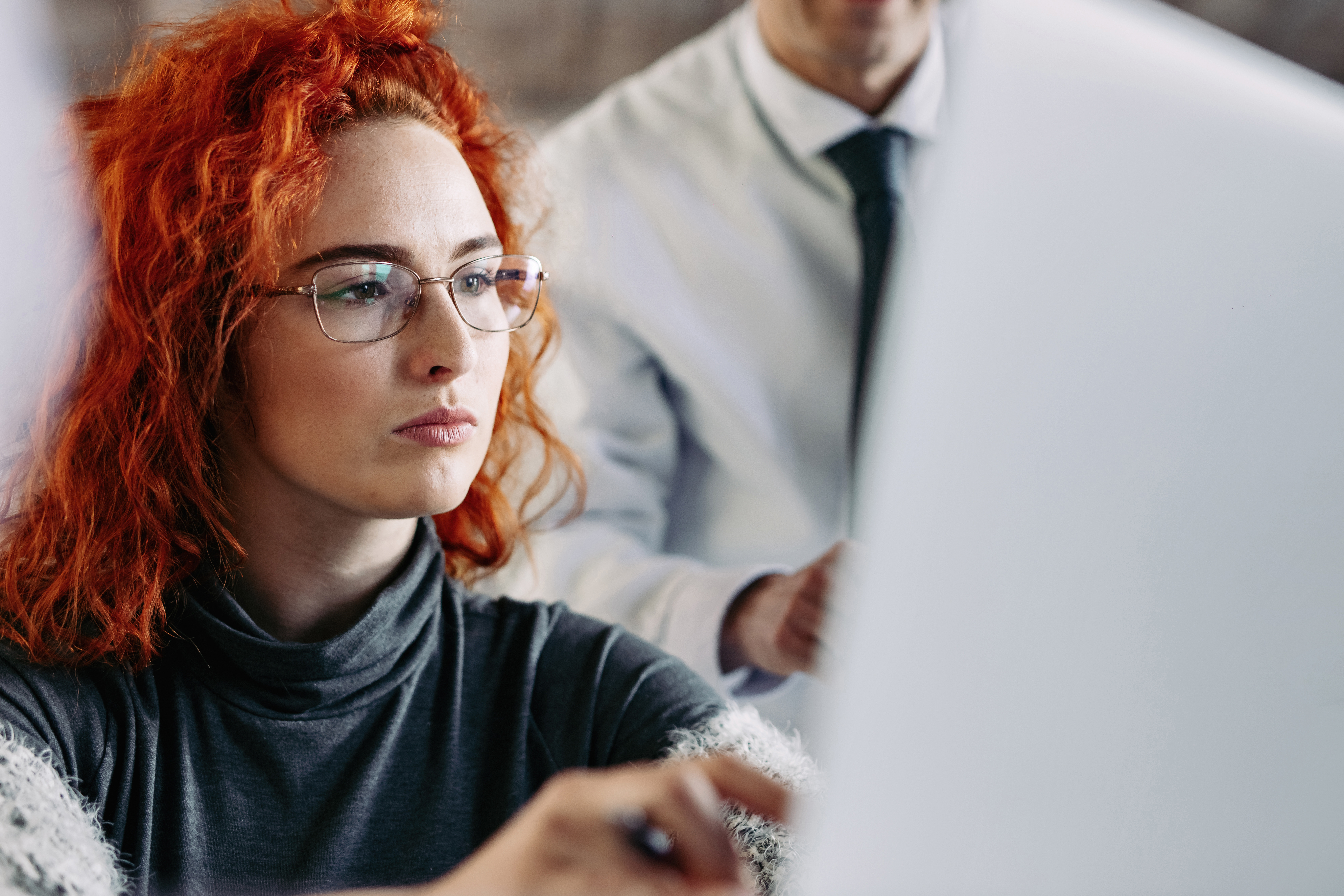 serious-young-businesswoman-working-computer-office-her-colleague-is-background